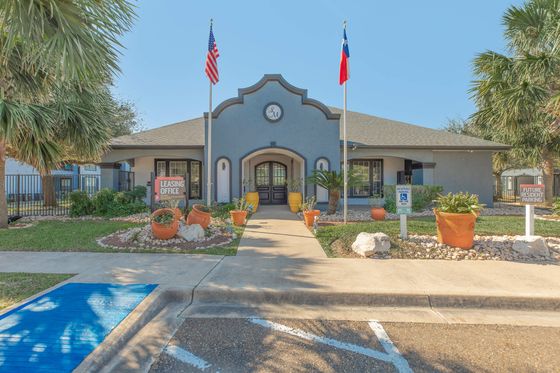 Welcoming leasing office with vibrant landscaping, flags, and accessible parking at a serene residential community.
