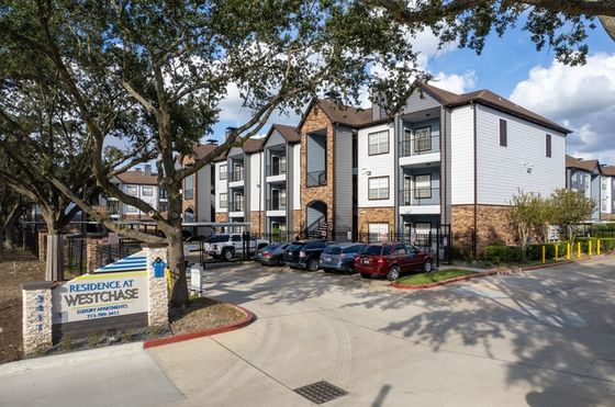 Inviting exterior view of Residence at Westchase luxury apartments featuring modern design, ample parking, and lush greenery, perfect for upscale living.