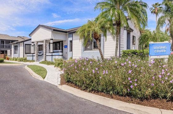 Inviting leasing center surrounded by vibrant landscaping and palm trees on a sunny day.