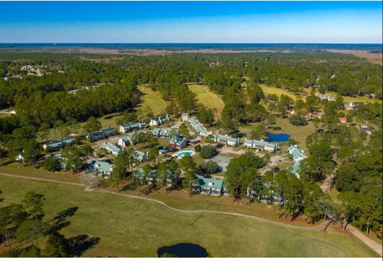 Stunning aerial view of a serene apartment complex nestled in lush greenery, featuring spacious buildings and a shimmering swimming pool.