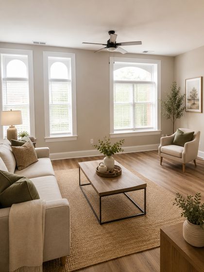 Bright and inviting living room with large windows, elegant wooden flooring, and tasteful modern decor, perfect for relaxation.