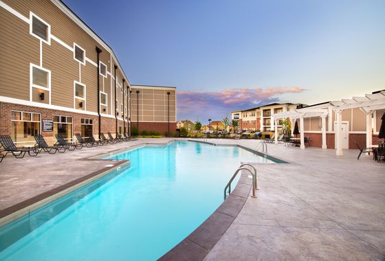 Inviting apartment complex featuring a sparkling swimming pool, surrounded by modern architecture and a serene outdoor lounge area.