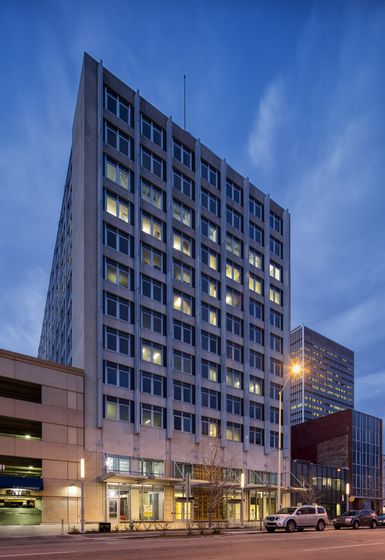 Modern high-rise apartment building illuminated warmly against an early evening sky, showcasing urban living at its finest.