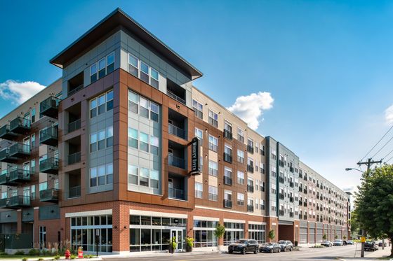 Modern apartment complex with contemporary design, featuring large windows and inviting balconies, basking in natural light against a clear sky.