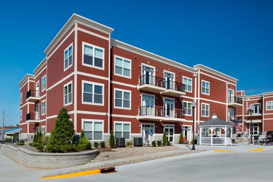 Charming red-brick apartment complex with balconies and a well-maintained garden, offering modern living in a serene neighborhood.