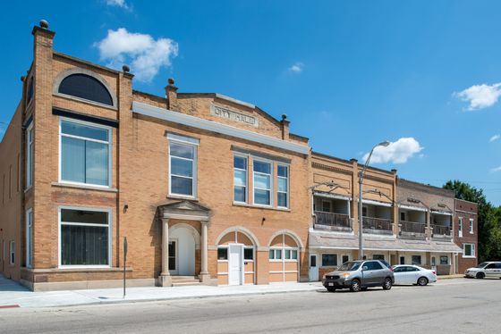 Historic building with charming brick facade, large windows, and elegant arches under a bright blue sky.