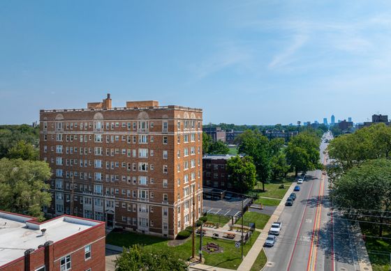 Charming historic apartment building with classic brick facade, nestled in a lush green neighborhood, offering urban views and convenient city access.