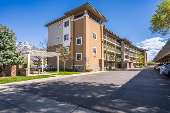 Modern apartment complex with mountain views, featuring outdoor seating and ample parking.
