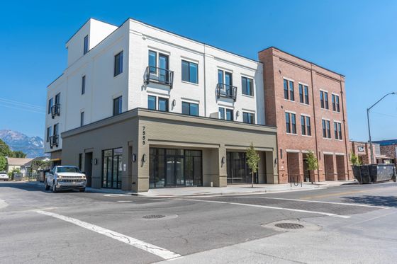 Contemporary apartment building with elegant brick and white facade located in a picturesque neighborhood with mountain views.