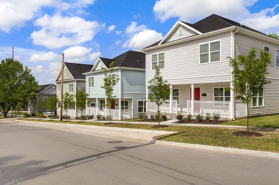 Charming neighborhood view displaying picturesque modern homes with inviting front porches and lush landscaping under a vibrant blue sky.
