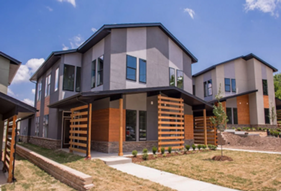 Modern townhouses with sleek exteriors, large windows, and inviting wooden accents set in a serene suburban neighborhood.