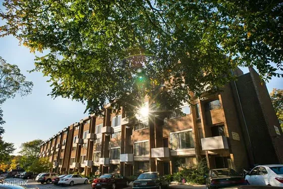 Charming apartment complex with modern architecture, nestled among lush green trees and ample parking space.