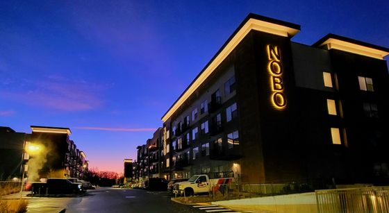 Modern apartment complex at dusk under a vibrant blue and purple sky, featuring elegant lighting and contemporary design.