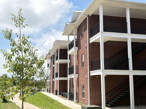 Elegant brick apartment building with spacious balconies and a charming landscaped yard, perfect for modern living.