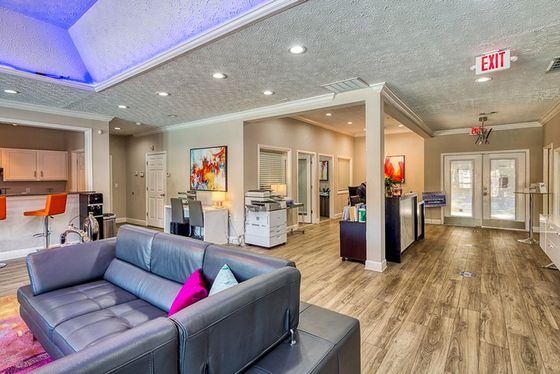Modern and inviting apartment interior with a contemporary seating area, vibrant artwork, and stylish bar stools, showcasing a chic and welcoming ambiance.