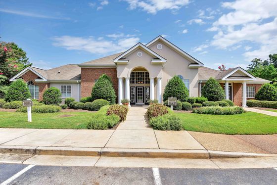 Elegant apartment building with manicured gardens and grand entrance, offering a welcoming and luxurious atmosphere.