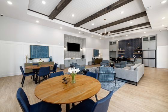 Elegant and spacious community lounge with modern furnishings and stylish decor, featuring open seating, wooden tables, and decorative accents.