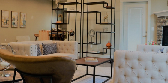 Chic living room with elegant tufted seating, modern open shelving, and a cozy fireplace backdrop.