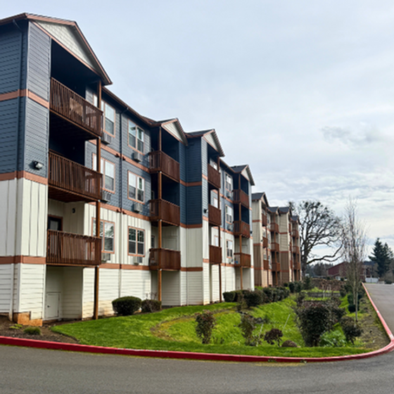 Modern apartment complex with balconies, lush landscaping, and ample parking, set in a serene neighborhood.