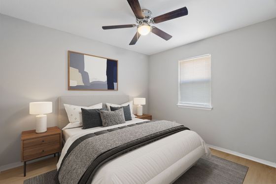 Chic and cozy bedroom with stylish decor, featuring a plush bed, elegant nightstands, modern ceiling fan, and gentle natural light from a window.