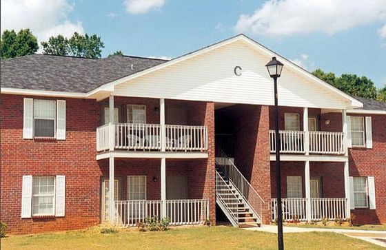 Charming brick apartment building with spacious balconies and lush greenery, perfect for enjoying serene views.