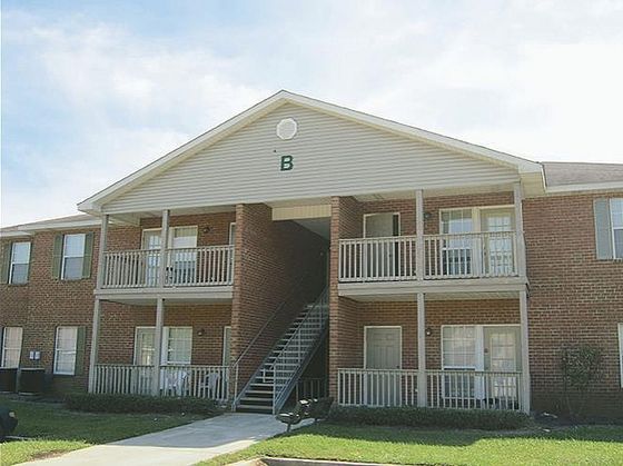 Charming two-story apartment building with inviting balconies and lush green surroundings.
