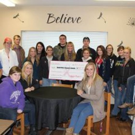 several people in clubhouse smiling for picture holding a large check