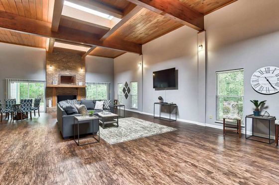 Expansive living space with high wood-beamed ceilings, modern fireplace, and stylish decor, creating a warm and inviting atmosphere.