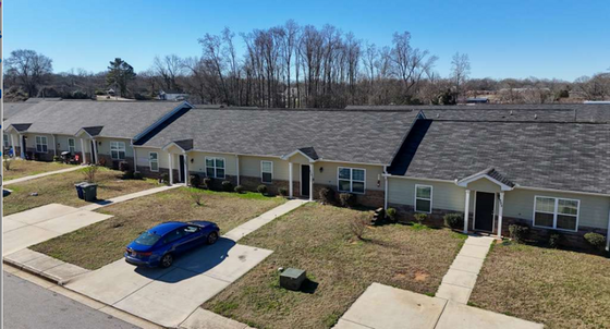 Charming row of modern townhouses with well-maintained lawns and driveways, set against a peaceful suburban backdrop.
