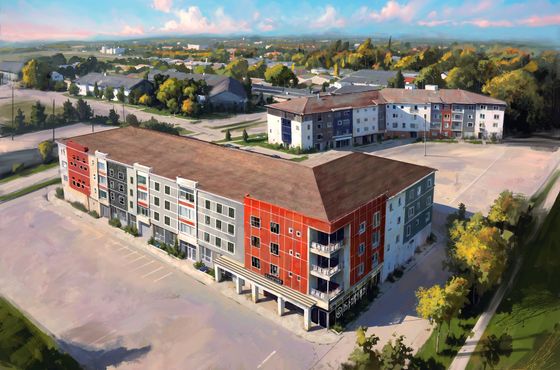 Vibrant aerial view of modern apartment complex with colorful facades, surrounded by lush greenery and spacious parking, creating an inviting residential community.
