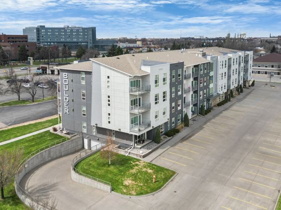 Modern apartment complex with sleek exterior and ample parking, showcasing contemporary urban living.