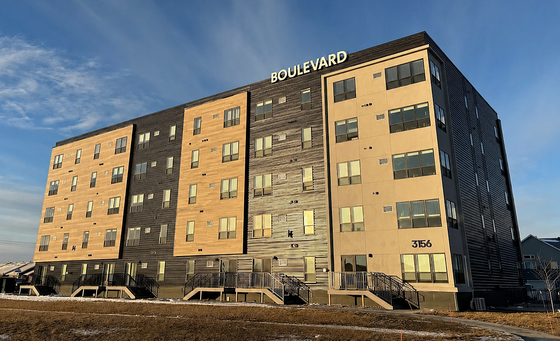 Modern Boulevard apartment building with stylish facade and multiple windows, basking in golden sunlight under a clear blue sky.