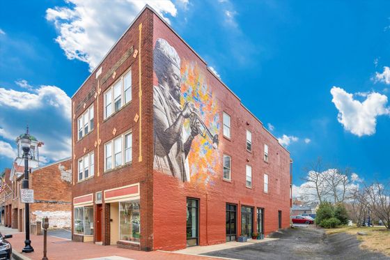 Vibrant urban apartment building with a large colorful mural on its facade against a bright blue sky.