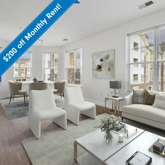 Bright and modern apartment living room with elegant decor, featuring cozy seating, chic dining area, and large windows for natural light. $200 off monthly rent!