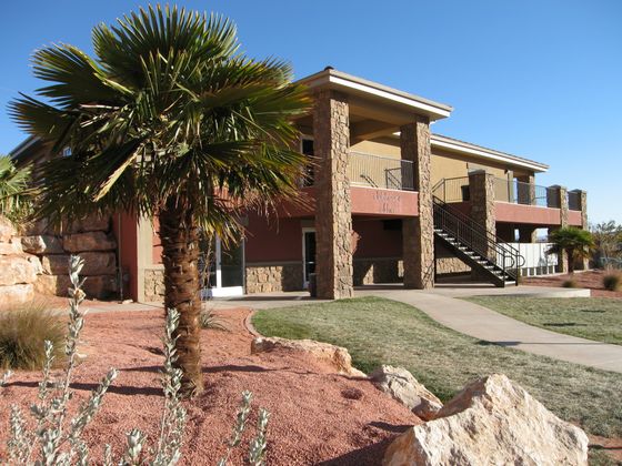 Charming clubhouse office with rustic stone architecture and lush landscaping, epitomizing desert elegance.