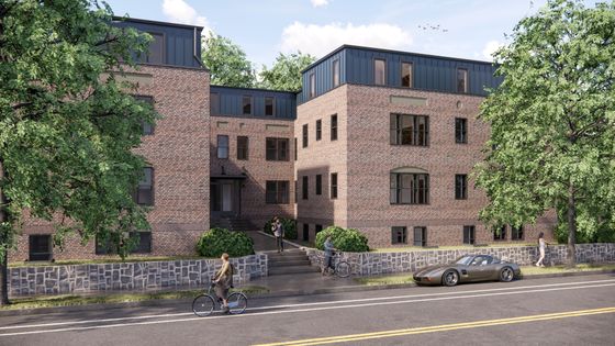 Charming brick apartment building with modern rooftop design, surrounded by lush greenery, featuring community-friendly sidewalks and convenient street parking.