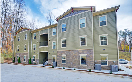 A light grey, three-story apartment building in the winter. | Hawksnest Common Apartments.