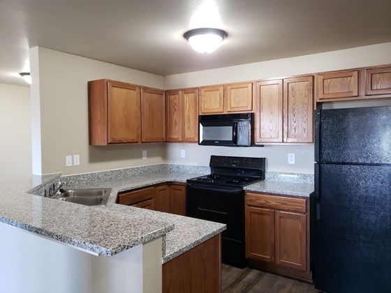 Modern kitchen with elegant granite countertops, sleek black appliances, and rich wood cabinetry, offering a stylish and functional space.