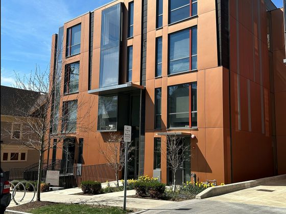 Modern apartment building with large windows, sleek design, and well-maintained landscape under a clear blue sky.