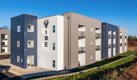 Modern apartment complex with sleek gray and white exterior, featuring multiple balconies and stylish architectural design.