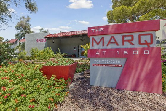 Entrance sign of The Marq at 1600 apartments surrounded by vibrant greenery.