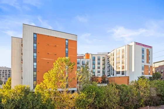 Contemporary apartment building with modern design, featuring vibrant orange and white exteriors, surrounded by lush greenery; now available for leasing at Cottonwood Westside in West Midtown Atlanta