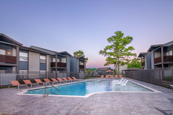 Inviting apartment complex with a serene outdoor pool area surrounded by modern buildings and lush greenery, perfect for relaxation and leisure.