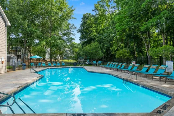Inviting luxury swimming pool area surrounded by lush greenery and elegant loungers, perfect for relaxation and outdoor enjoyment.
