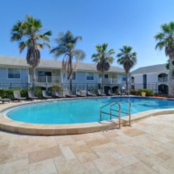 Royal Breeze Apartments Inc, exterior, sparkling blue swimming pool, palm trees, white buildings