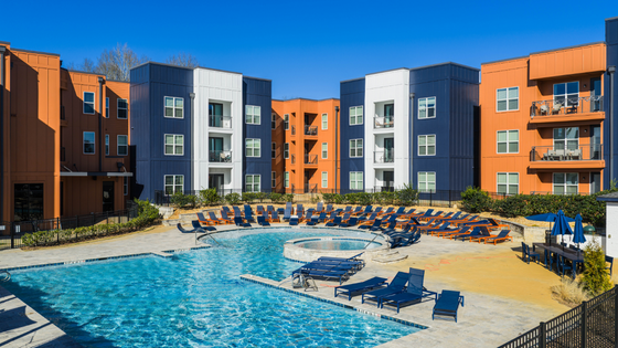 Vibrant apartment complex with modern architecture, featuring a stunning swimming pool area surrounded by stylish lounge chairs and eye-catching orange and blue building facades.