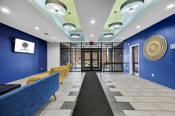 Modern apartment lobby featuring vibrant blue walls, cozy seating, and elegant lighting fixtures, offering a welcoming entrance.