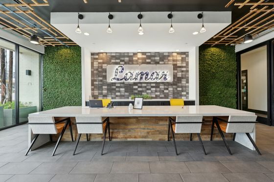 Elegant modern office space with greenery walls and sleek lighting, featuring a large communal table and stylish decor.