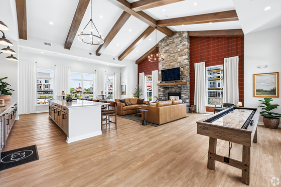 Inviting living space with high ceilings, wood beams, stone fireplace, and modern kitchen featuring a large island, perfect for entertaining.