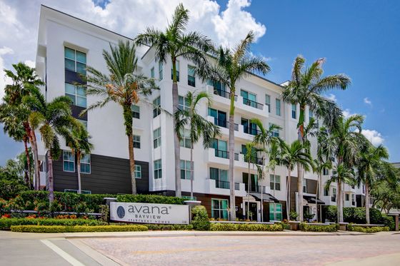 Avana Bayview, exterior, wall white building, 5 levels, palm trees, property sign
